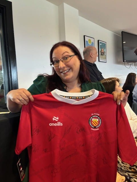 Stephanie Austin holding a signed FC United of Manchester shirt won in the charity raffle at the North Manchester International Women’s Day Business Awards.