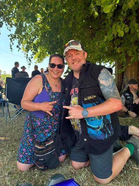 Steph and Pete kneeling together under a tree at EddFest, smiling, earlier in the day.