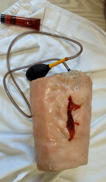 Custom-built wearable wound packing trainer with a moulded wound, tubing and hand pump. Prima Cura Training delivering FAW to learners.